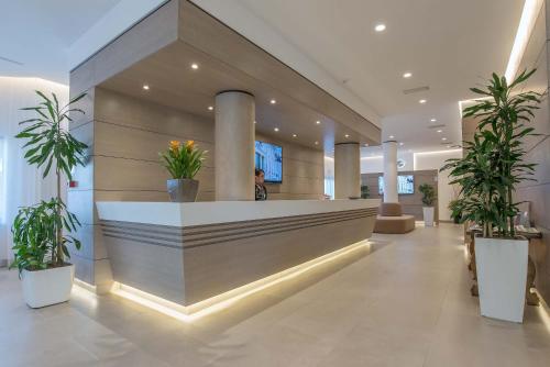 a woman is standing in a lobby with plants at Hotel La Giocca in Rome