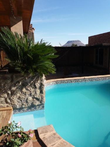 a blue swimming pool with plants in a yard at Skietberg Lodge in Colesberg