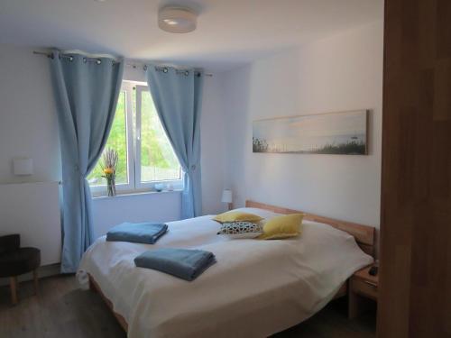 een slaapkamer met een bed met blauwe gordijnen en een raam bij Ferienwohnung Traumsegler in Juliusruh