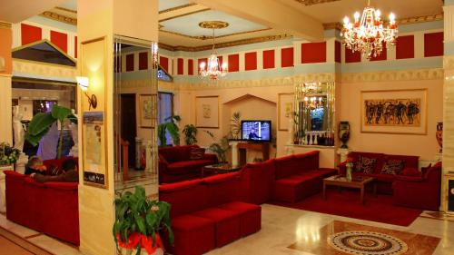 a living room with red couches and a tv at Hotel Kosta Famissi in Kalabaka