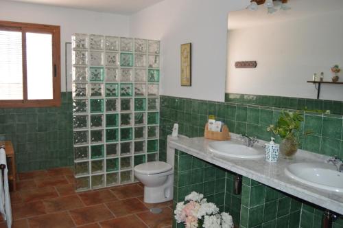a green tiled bathroom with two sinks and a toilet at El Olivo del Moreno in Hornachuelos