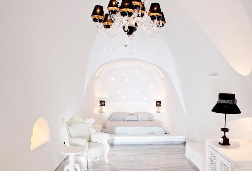 Habitación blanca con cama y lámpara de araña. en Asteras Villas en Fira