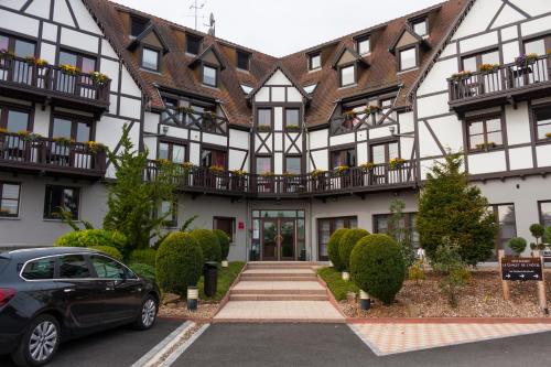 a building with a car parked in front of it at Hôtel Restaurant Les Alizés in Lipsheim