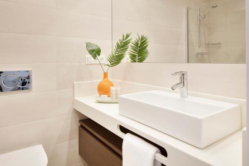 ein weißes Badezimmer mit einem Waschbecken und einem Spiegel in der Unterkunft Marina Suite by FeelFree Rentals in San Sebastián