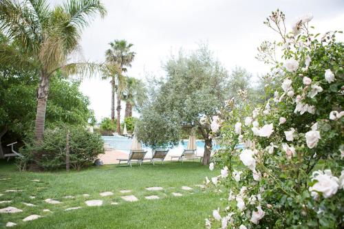 a yard with two chairs and trees and a pool at Agriturismo Il Granaio Hotel & SPA in Modica