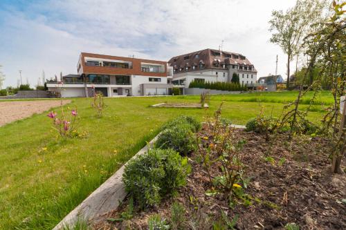 a building with a yard with flowers in the grass at Hôtel Restaurant Les Alizés in Lipsheim