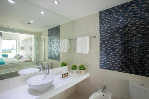 a bathroom with a sink and a toilet and a mirror at King Evelthon Beach Hotel & Resort in Paphos City