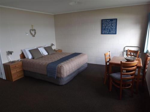 a bedroom with a bed and a table and chairs at Harbour View Motel in Coromandel Town