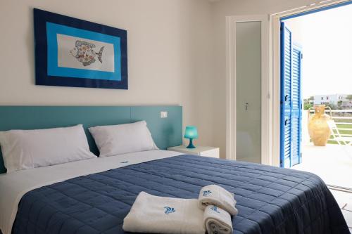 a bedroom with a blue bed and a large window at La Dimora Salento in Carovigno