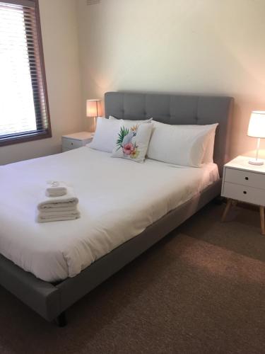 a bedroom with a large bed with white sheets and pillows at Acorn Lodge in Bright