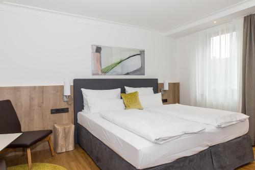 a bedroom with a large bed with white sheets and yellow pillows at Hotel Goldenes Rad in Ulm