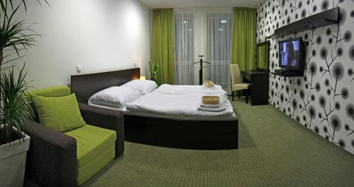 a bedroom with a bed and a chair and a tv at Penzion Luxury in Rožňava
