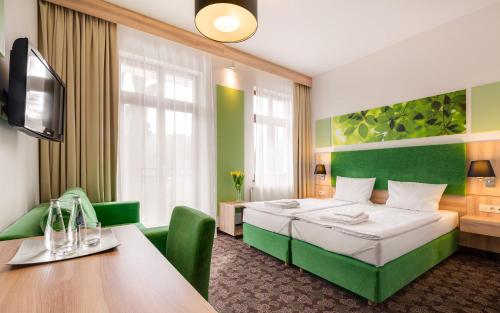 a hotel room with a bed and a table at Cottonina Hotel & Mineral SPA Resort in Świeradów-Zdrój
