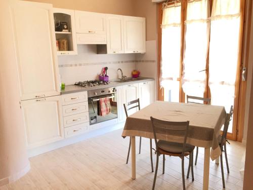 アルゲーロにあるCozy Apartment in Algheroのキッチン(白いキャビネット、テーブル、椅子付)