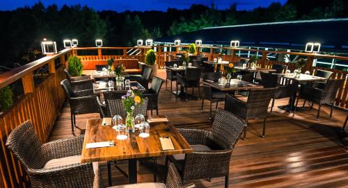 a restaurant with tables and chairs on a deck at Akademia Kuraszków in Kuraszków