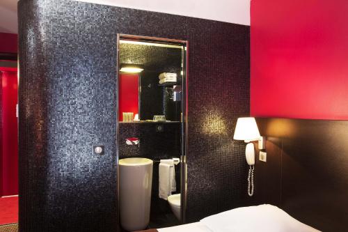 La salle de bains est pourvue d'un mur noir et d'un miroir. dans l'établissement Hôtel Sophie Germain, à Paris