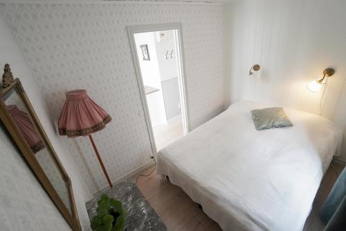 a small bedroom with a bed and a lamp at Anfasteröd Gårdsvik - Badstugorna in Ljungskile