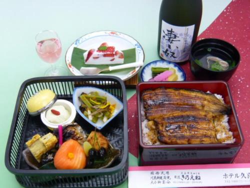 Kuki的住宿－庫克酒店，一张桌子,上面放着两个容器的食物和一瓶葡萄酒
