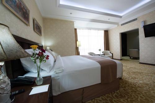 a hotel room with a bed and a vase of flowers at Capital Hotel and Spa in Addis Ababa