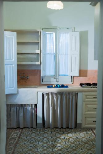 a kitchen with white cabinets and a sink at Petrarussa Dimora Storica in Morciano di Leuca