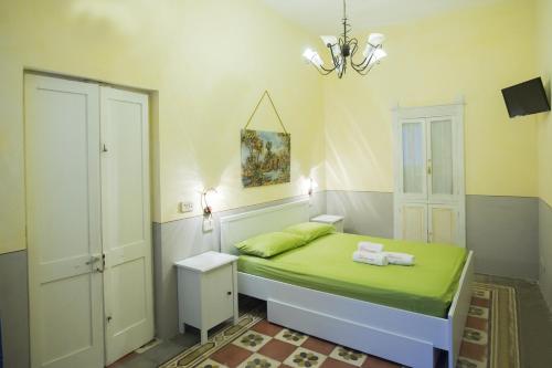 a small bedroom with a green bed and a chandelier at Petrarussa Dimora Storica in Morciano di Leuca