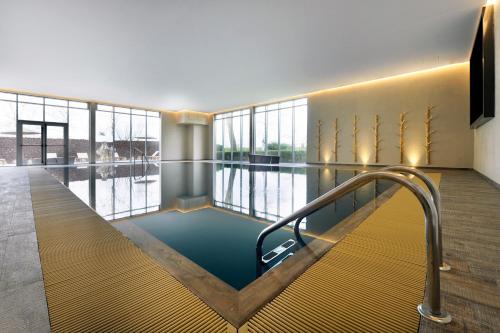 een zwembad in een gebouw met een groot raam bij Van der Valk Hotel Beveren in Beveren