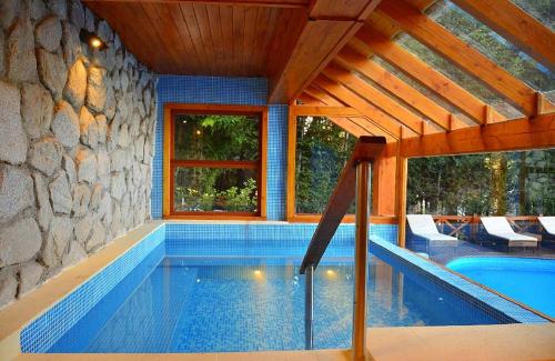 uma piscina numa casa com uma parede de pedra em Dos Bahias Lake Resort em Villa La Angostura