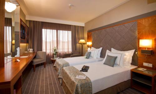a hotel room with two beds and a desk at Tugcan Hotel in Gaziantep