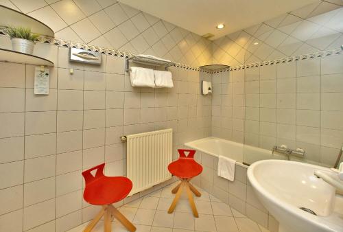 ein Badezimmer mit zwei roten Stühlen neben einer Badewanne in der Unterkunft Hôtel des Récollets in Sarlat-la-Canéda