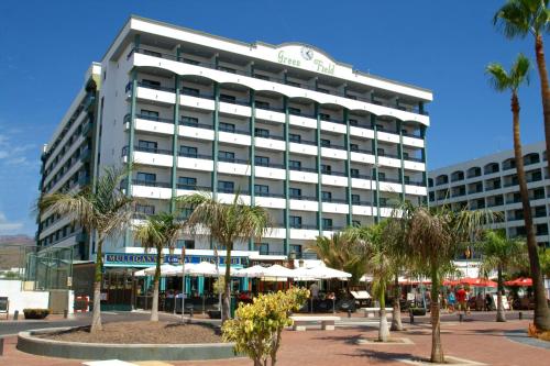 a large white building with palm trees in front of it at Hotel Green Field in Playa del Ingles