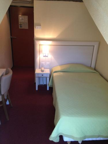 a small bedroom with a bed and a table at Hotel Elysée in Lyon