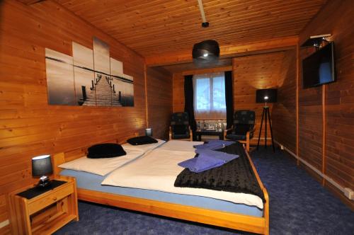 um quarto com uma cama grande num quarto de madeira em Penzión Pastierňa em Dedinky