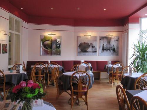ein Esszimmer mit Tischen, Stühlen und Gemälden an den Wänden in der Unterkunft Hotel Haus Martens in Hannover