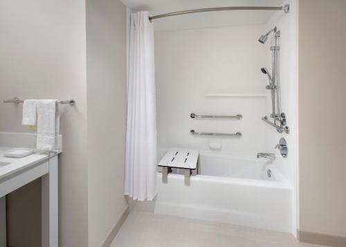 La salle de bains blanche est pourvue d'une douche et d'une baignoire. dans l'établissement Hayes Street Hotel Nashville, à Nashville