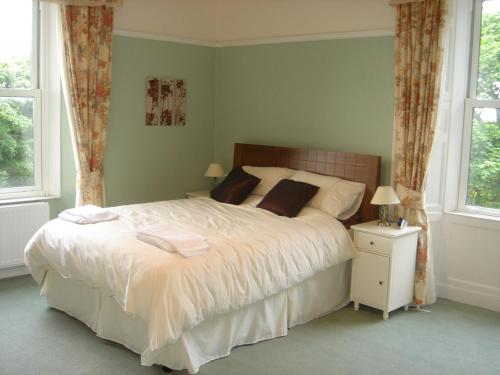 a bedroom with a large white bed and two windows at Croft Hill Guest House in Whitehaven