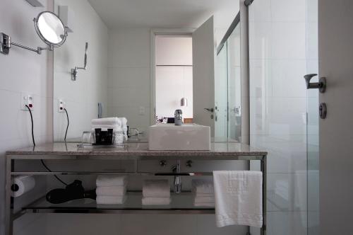 a white bathroom with a sink and a mirror at H Niteroi Hotel in Niterói