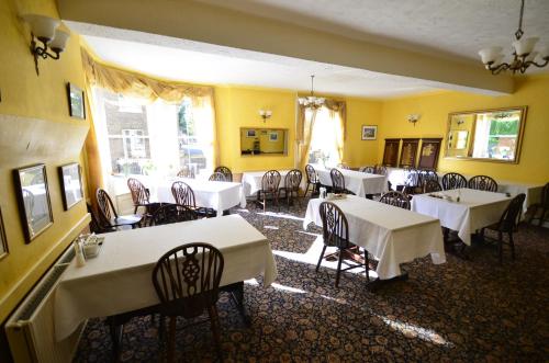 a dining room with white tables and chairs and yellow walls at Wereham House in Thetford
