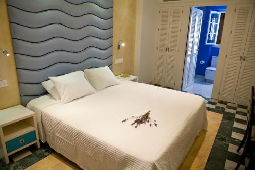 sypialnia z białym łóżkiem z kwiatem w obiekcie Hostal El Alojado de Velarde w mieście Conil de la Frontera