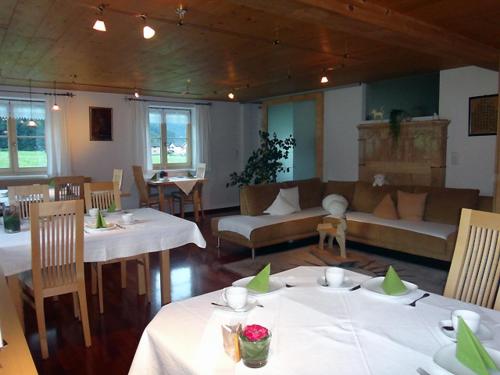 a restaurant with white tables and a couch and chairs at Gästehaus Appartements Egender in Bezau