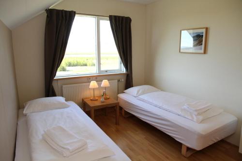 a bedroom with a bed, a desk and a lamp at Eyjólfsstadir Guesthouse in Egilsstaðir