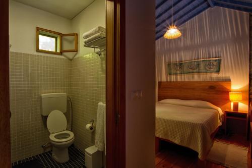 een badkamer met een bed en een toilet in een kamer bij Casa de Pedra in Ribeira Quente