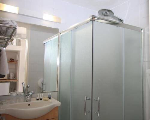 W łazience znajduje się szklana kabina prysznicowa i umywalka. w obiekcie Neve Shalom Hotel w mieście Neve Shalom