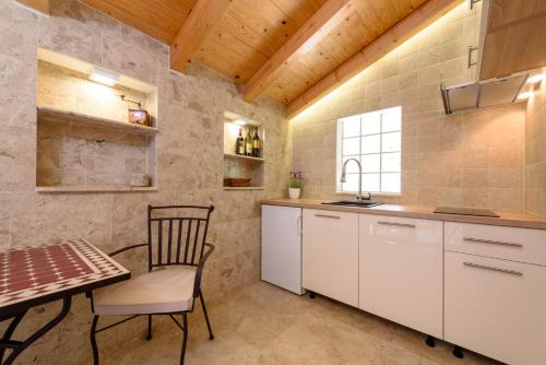 a kitchen with white cabinets and a table and chair at Villa Kudelik - Stone Story in Trogir