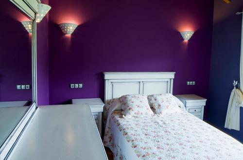 a bedroom with purple walls and a white bed at Apartamentos Rurales El Fresnu in Silvamayor