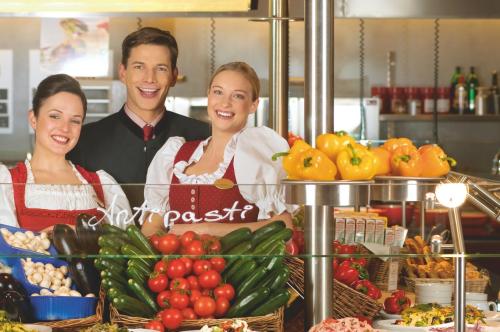 a man and two women standing behind a counter with fruits and vegetables at Rosenberger Motel Völkermarkt in Völkermarkt