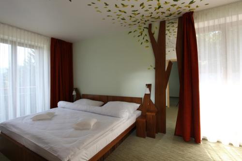 a bedroom with a large bed with a tree on the ceiling at Beltine Forest Hotel in Ostravice