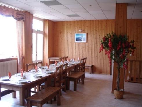 a dining room with wooden tables and chairs and flowers at Résidence Les Dômes in Murol