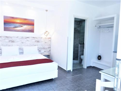 a white bedroom with a bed and a bathroom at Anemos Studios in Adamas