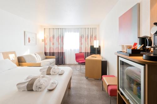 Habitación de hotel con 2 camas y sala de estar. en Novotel Lisboa, en Lisboa