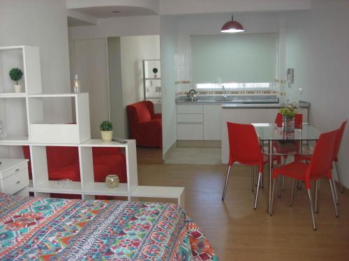 1 dormitorio con 1 cama y 1 mesa con sillas rojas en Rent Apart Caballito 2 en Buenos Aires
